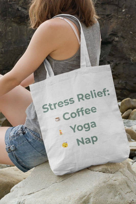 Mental health tote bag with a person holding a tote bag with 'Stress Relief: Coffee Yoga Nap' text on rocks.