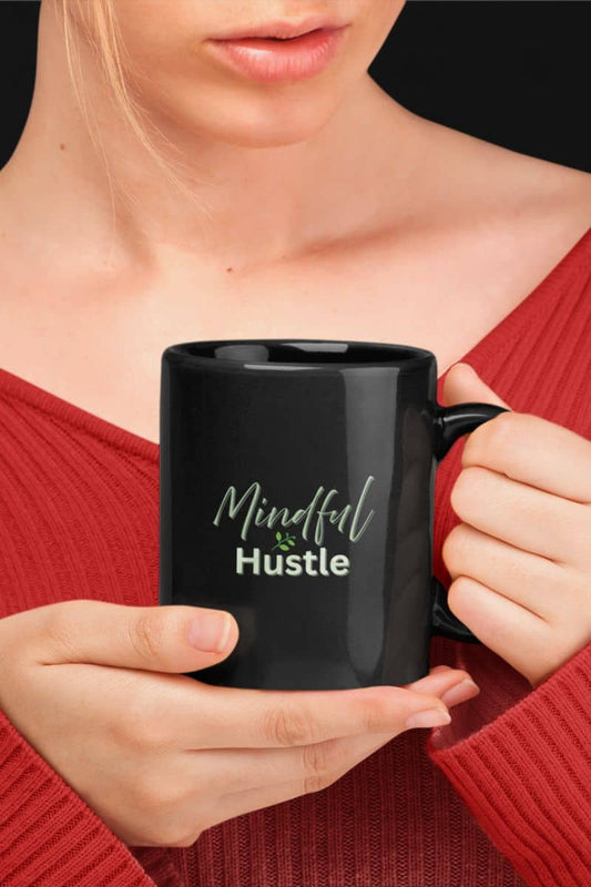 Mindful morning coffee mug with a person holding a black mug with 'Mindful & Hustle' text, wearing a red top.