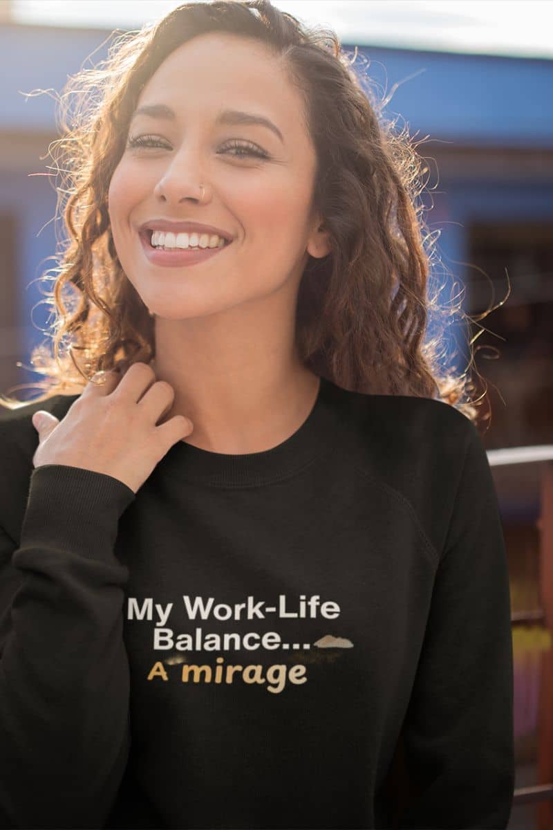 Minimalist casual sweatshirt with a woman wearing a black sweatshirt with text 'My Work-Life Balance... A mirage' in an outdoor setting.
