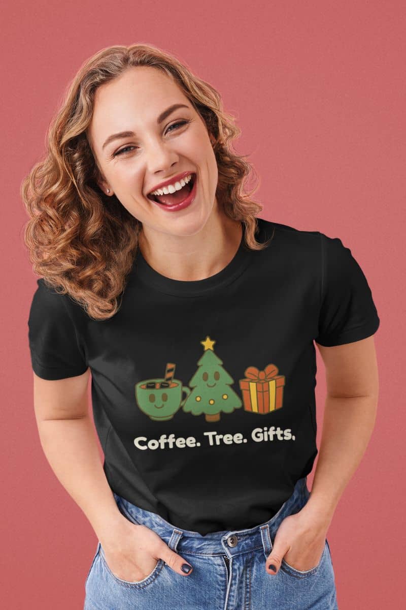 Minimalist holiday icon shirt with a woman wearing a black t-shirt with Christmas-themed graphics and text 'Coffee. Tree. Gifts.' on a pink background
