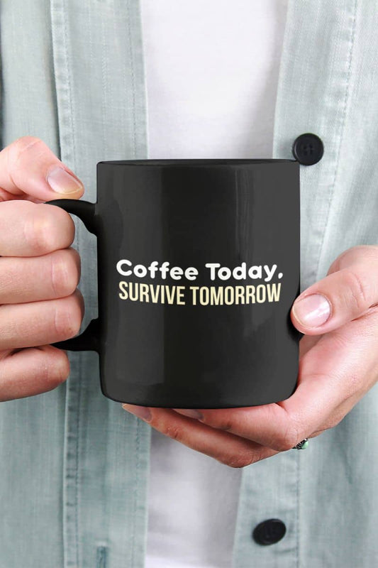 Morning coffee mug with a black mug with text 'Coffee Today, Survive Tomorrow' held by a person.