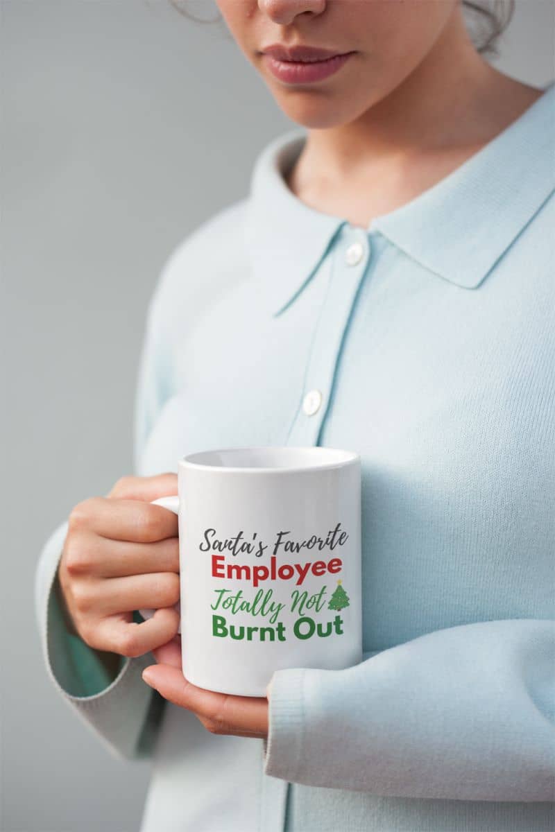 Morning meeting survival cup with a person holding a mug with 'Santa's Favorite Employee Totally Not Burnt Out' text