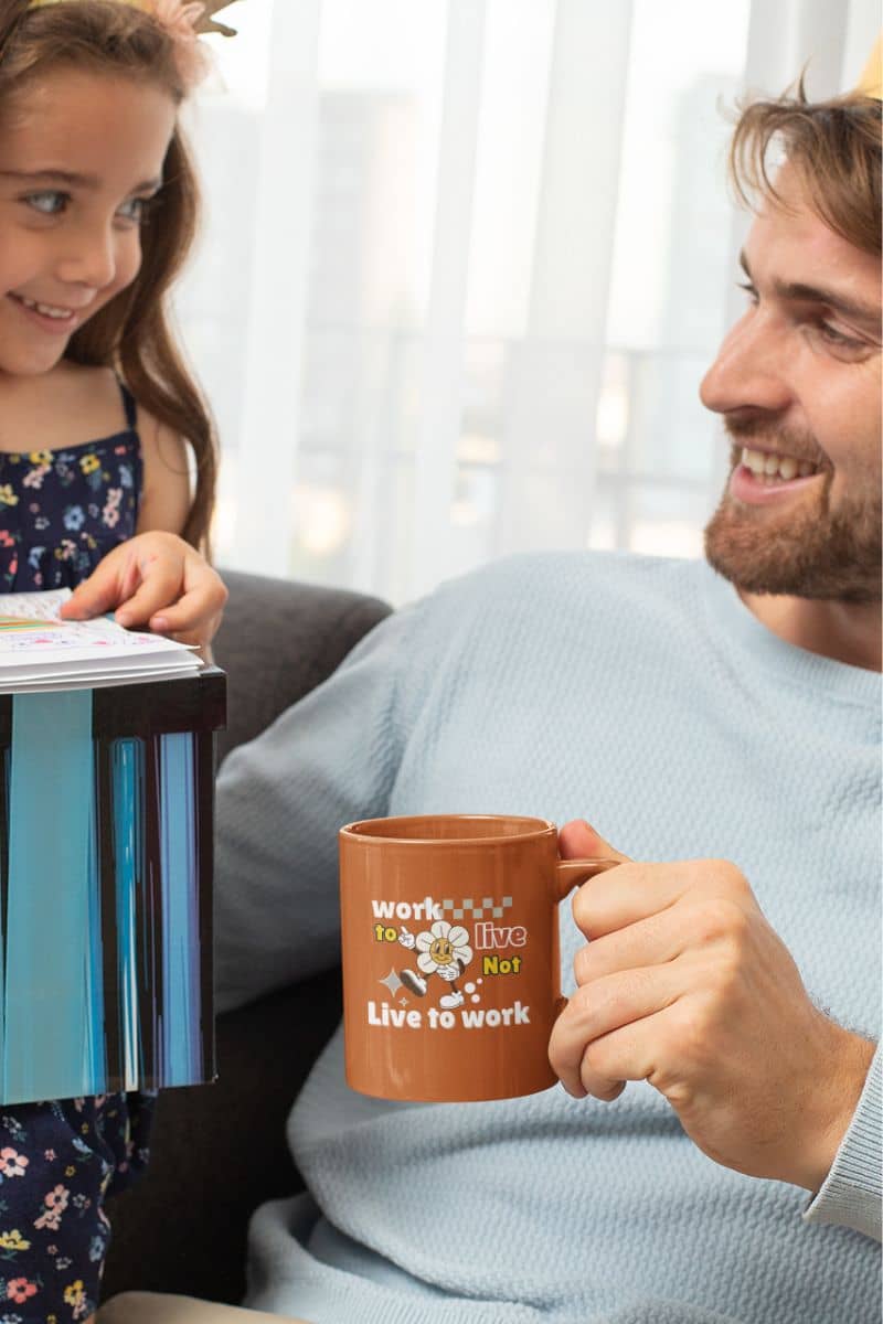 Motivational ceramic mug with the dad wearing a birthday hat and talking happily to his daughter while holding a cup of coffee