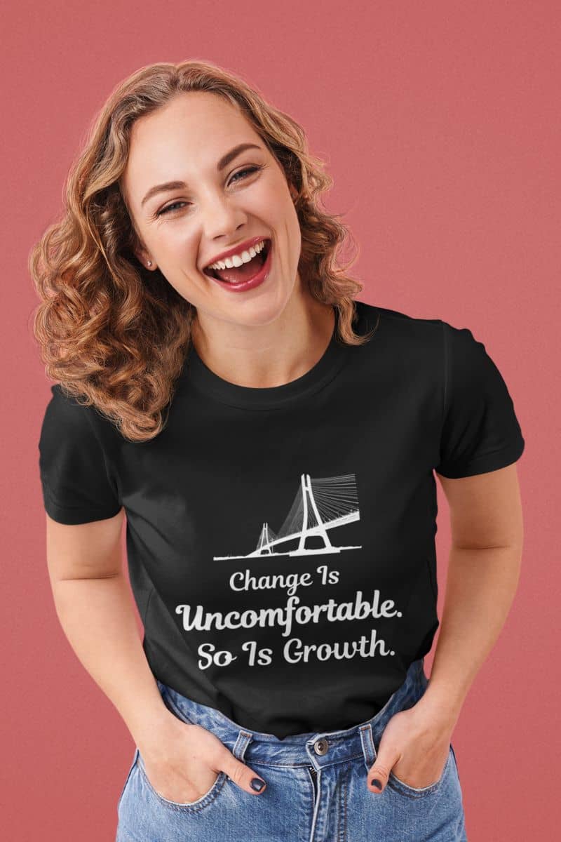 Personal growth t-shirt with a woman wearing a black t-shirt featuring a motivational quote 'Change Is Uncomfortable. So Is Growth' on a pink background
