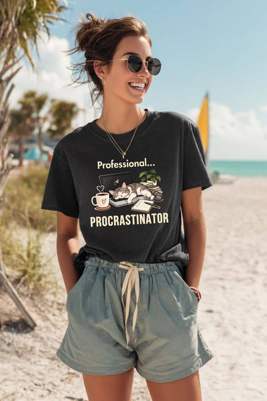 Procrastination shirt with a woman wearing a t-shirt featuring the text ' Professional Procrastinator', standing at the beach