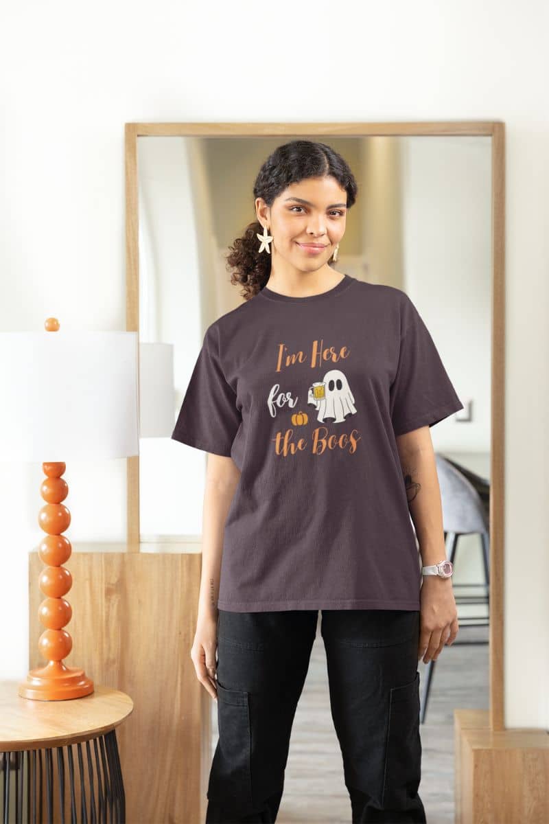 Pumpkin Halloween tee featuring a girl posing in front of the mirror in a brown T-shirt with the text “I’m Here for the Boos.”