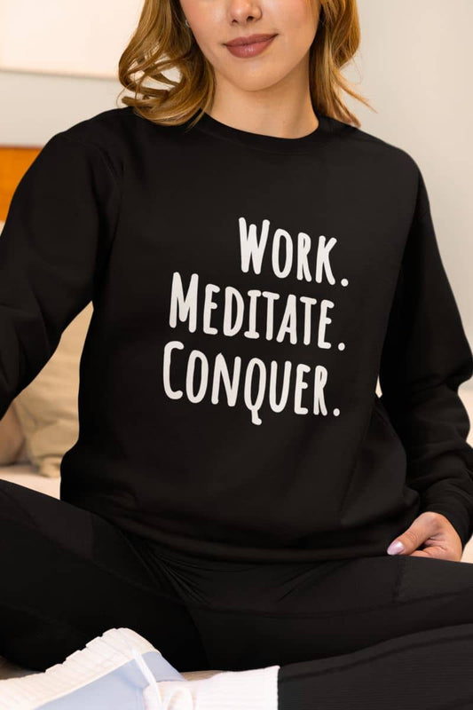 Relaxed fit meditation sweatshirt with a person wearing a black sweatshirt with 'Work. Meditate. Conquer.' text.