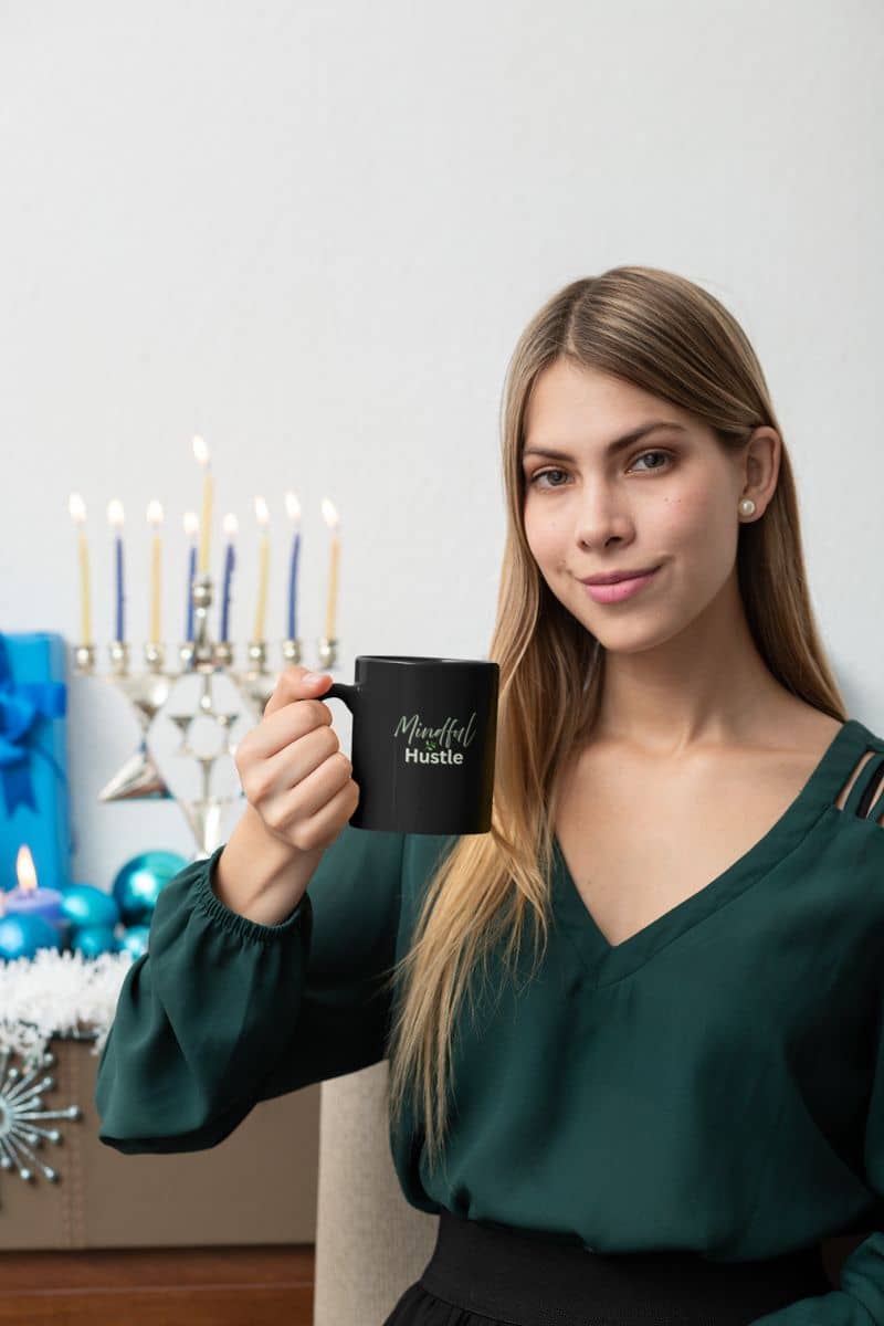Relaxed start coffee mug with a woman holding a black mug with text in front of a decorated room with candles and blue lights.