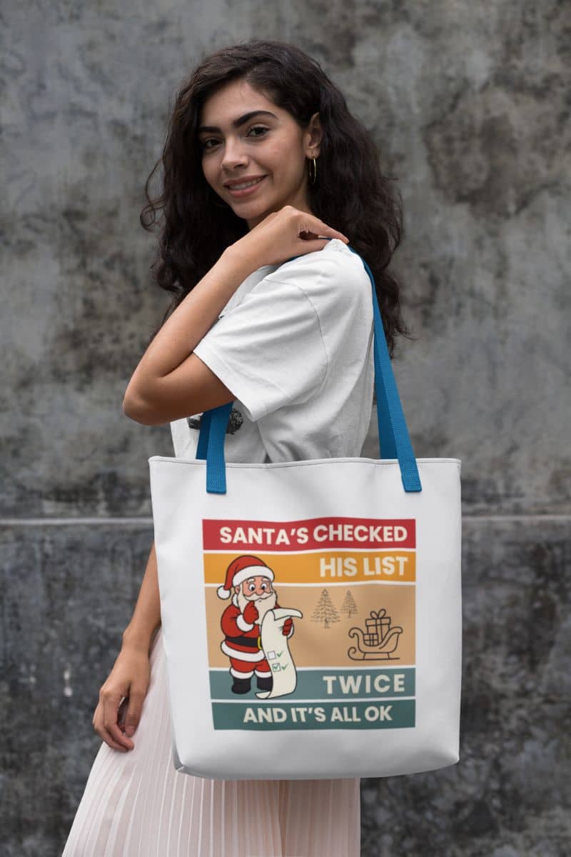 Retro christmas tote bag with a woman holding a tote bag with text 'Santa's Checked His List Twice And It's All Ok'