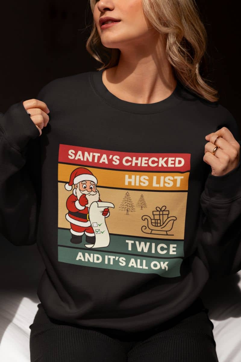 Retro santa christmas sweatshirt with a woman in a black sweatshirt featuring the quote 'Santa's Checked His List Twice And It's All Ok'