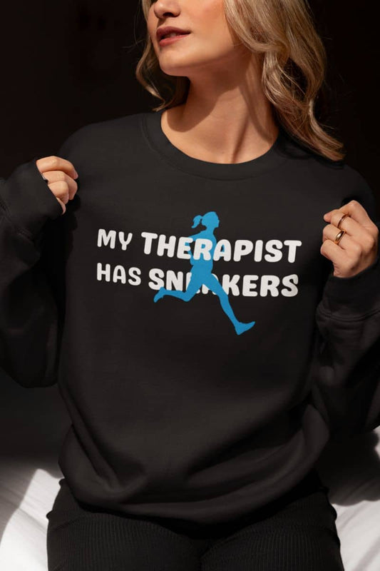 Running sweatshirt with a person wearing a black sweatshirt with text 'My Therapist Has Sneakers' and graphic design.