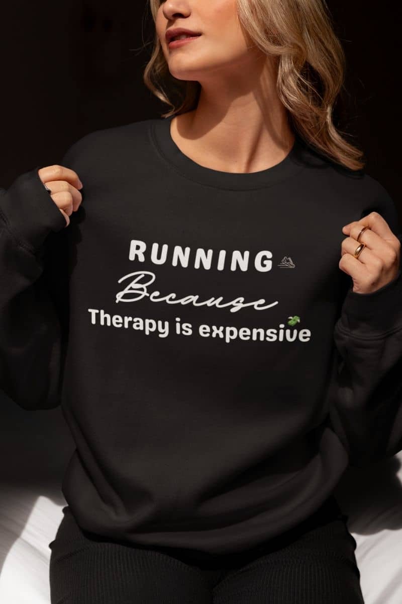 Running therapy sweatshirt with a person wearing a black sweatshirt with text 'RUNNING Because Therapy is expensive' on a dark background