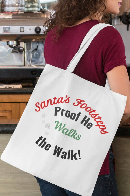Santa's footsteps tote bag with a person holding a tote bag with text 'Santa's Footsteps - Proof He Walks The Walk!' in a casual setting