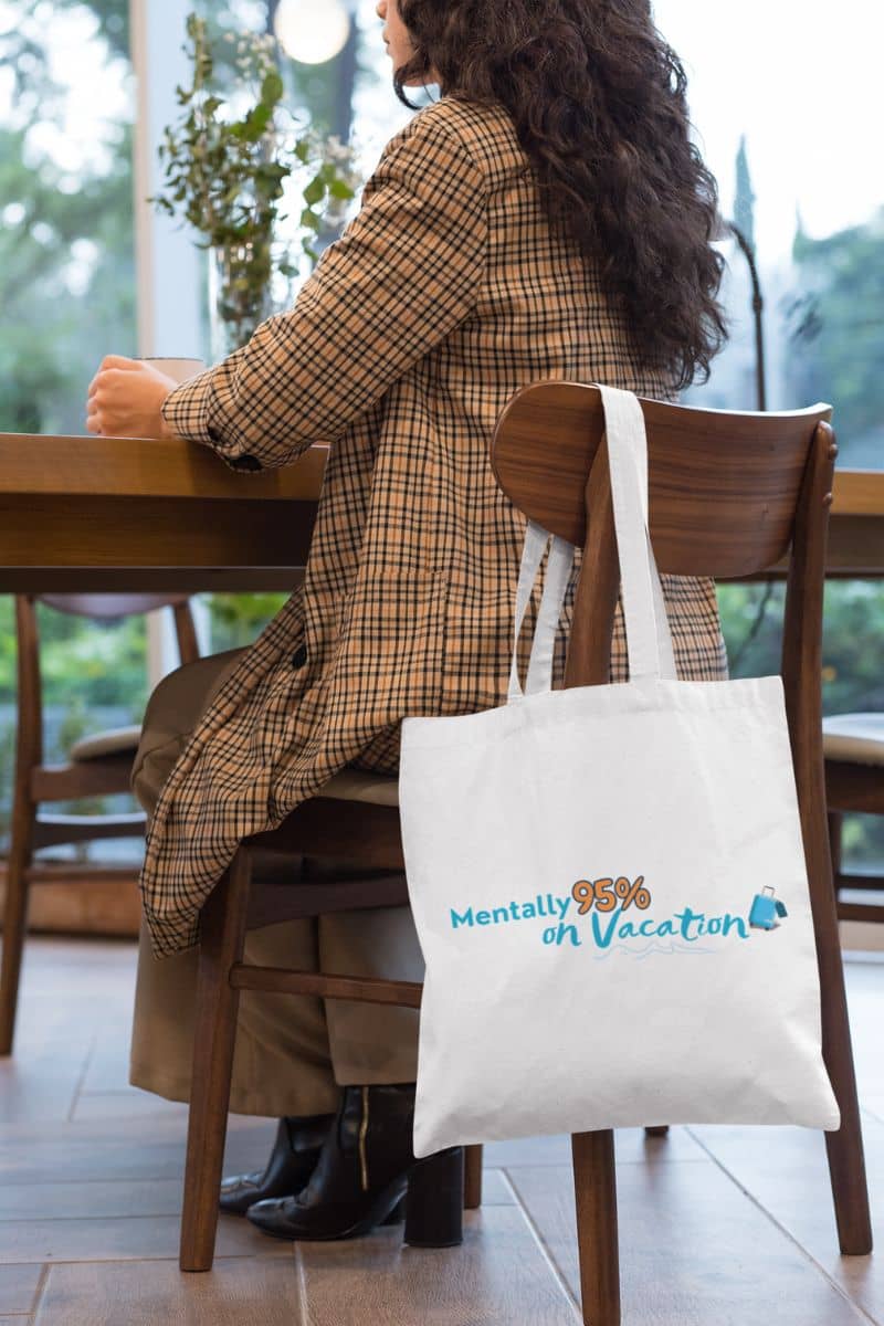 Seaside mood shopping bag with a person sitting at a table with a tote bag featuring 'Mentally 98% on Vacation' text.