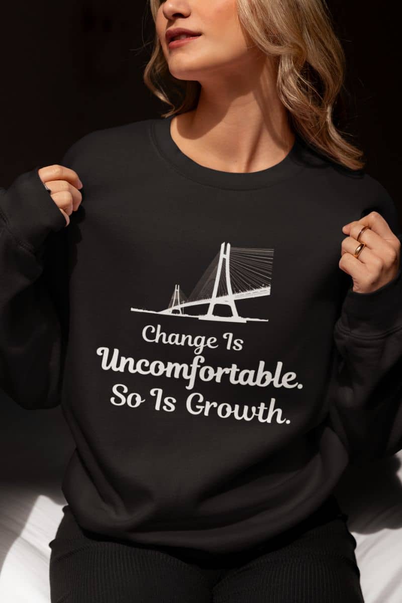 Self improvement sweatshirt with a person wearing a black sweatshirt with a motivational quote 'Change Is Uncomfortable. So Is Growth' and graphic design.