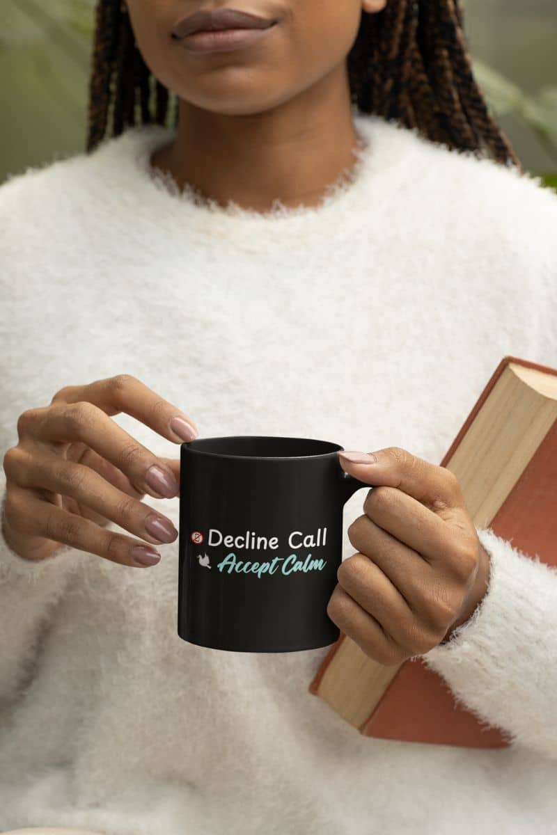 Spiritual quote mug with a person holding a black mug with text 'Decline Call Accept Calm', wearing a white sweater.