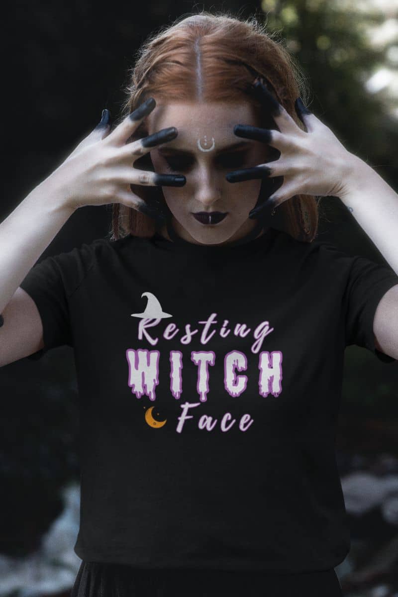 Spooky season graphic tee with a person featuring a black t-shirt with 'Resting Witch Face' text, standing against a dark background.