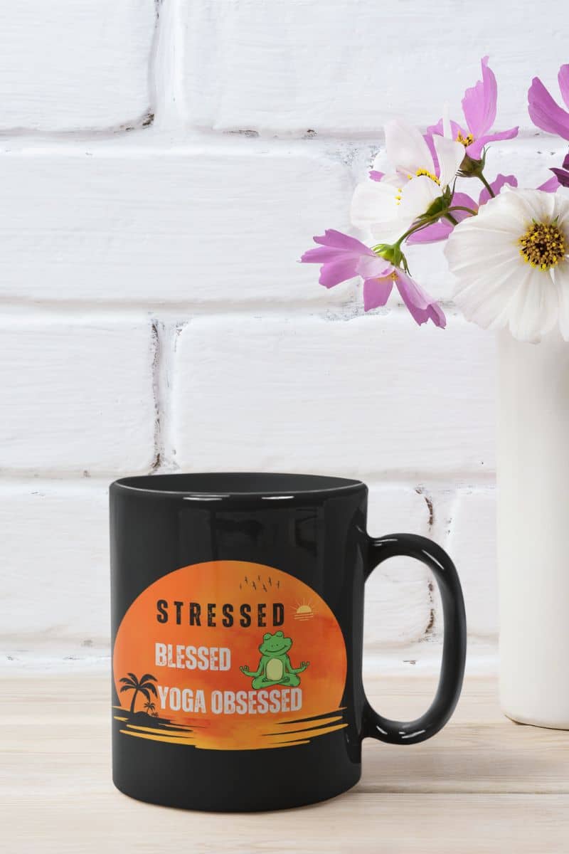 Stressed, blessed, yoga obsessed mug with the cup lying on the table next to the small vase