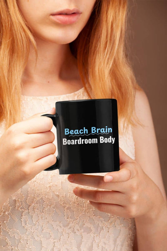 Vacation mindset coffee mug with a person holding a black mug with text 'Beach Brain Boardroom Body'.