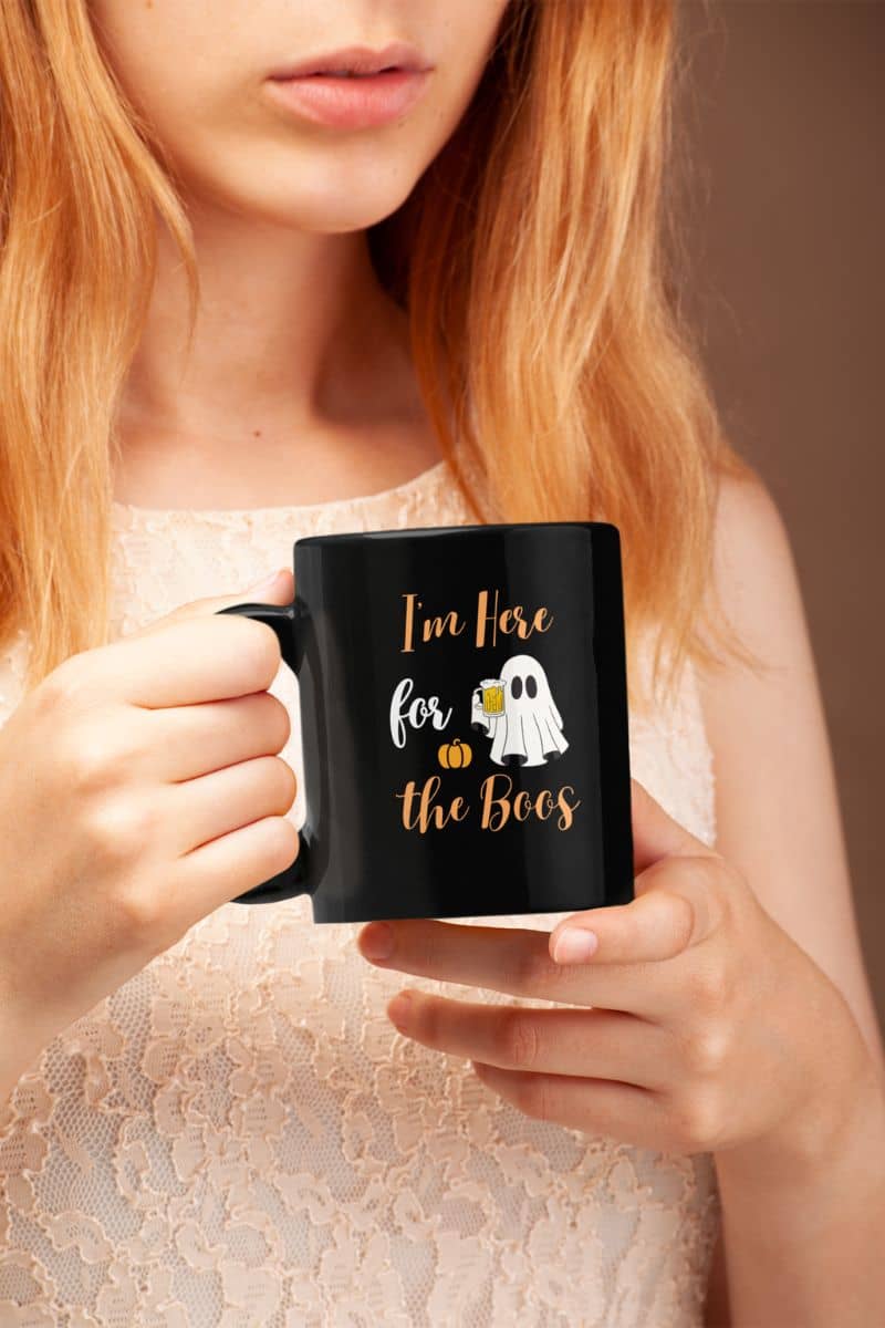 Witchy coffee mug with a person holding a black mug with Halloween-themed text and graphics.