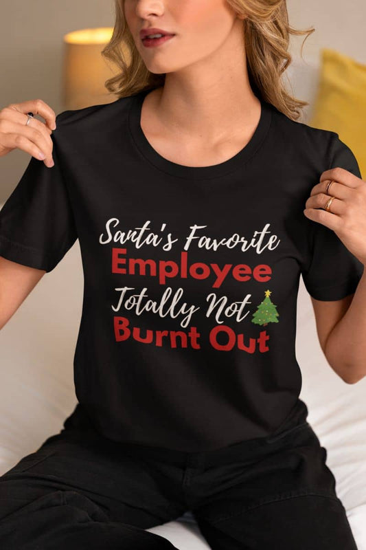 Witty office humor tee with a person wearing a black t-shirt with text 'Santa’s Favorite Employee Totally Not Burnt Out'