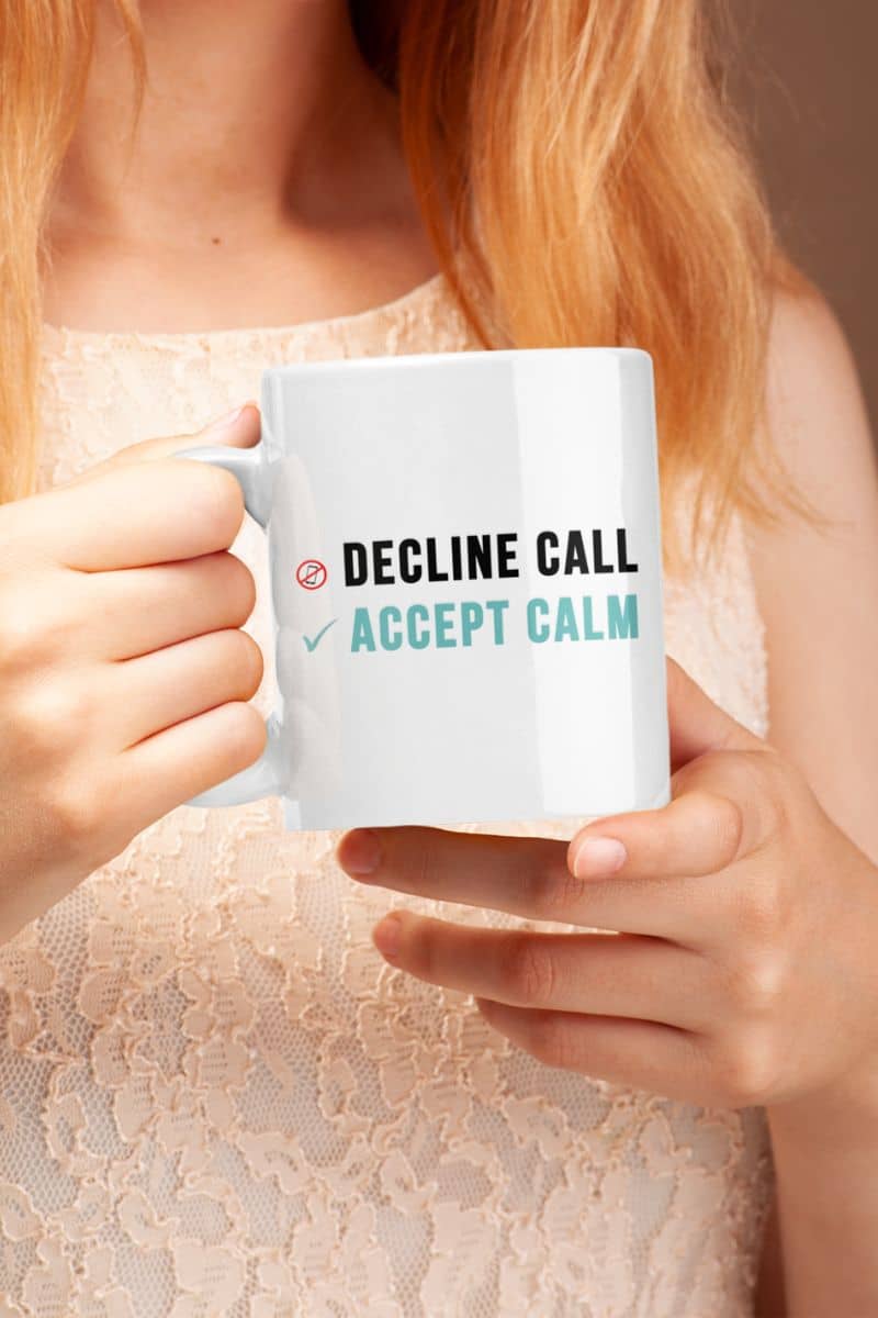 Work life balance mug with a person holding a mug with text 'DECLINE CALL ACCEPT CALM' against a neutral background