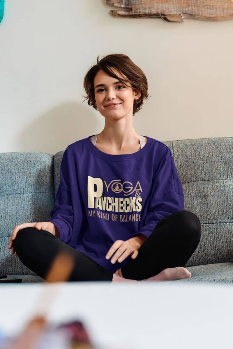 Yoga and paychecks sweatshirt with a short haired girl sitting on the sofa with a bright smile