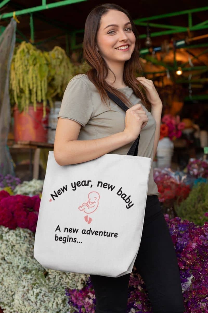 baby announcement tote with a young girl holding a tote bag with text 'New year, new baby. A new adventure begins...'