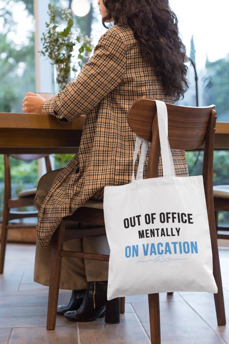 beach carryall bag with a person sitting at a table with a tote bag that says 'Out of Office Mentally On Vacation'.