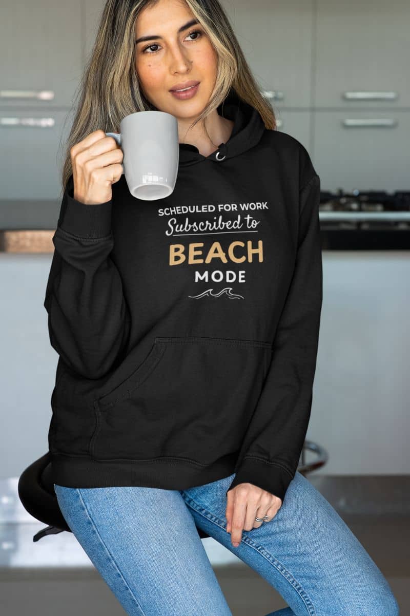 beach sweatshirt with a person wearing a black hoodie with text 'Scheduled for Work. Subscribed to Beach', holding a mug in a kitchen.
