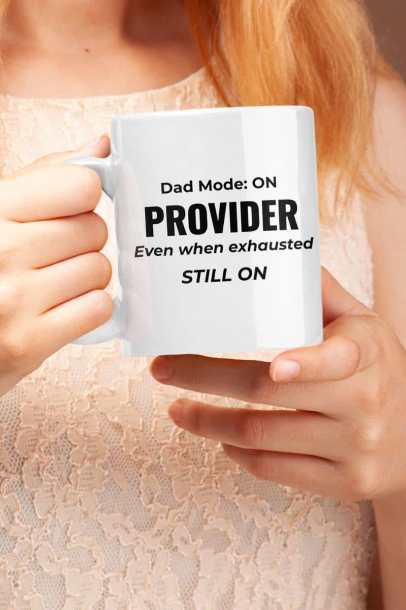 best dad mug with a person holding a white mug with text 'Dad Mode: On. Provider. Even when exhausted. Still on' against a neutral background.
