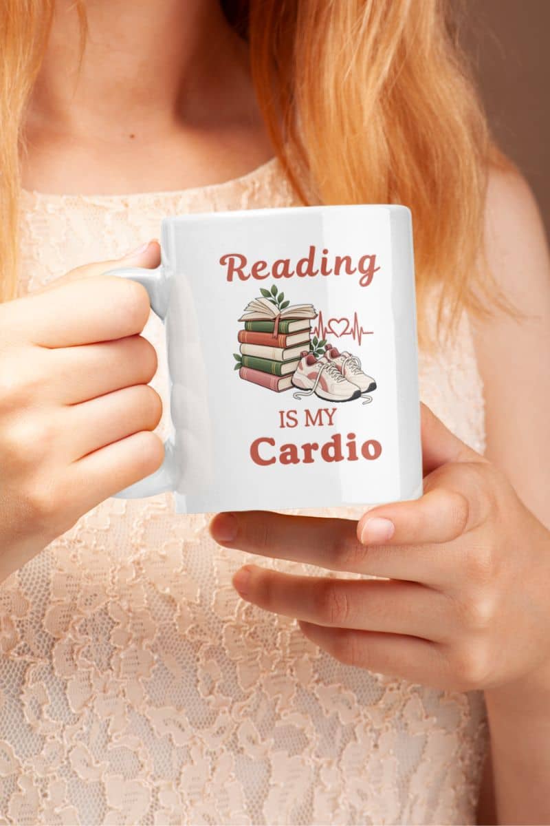 book lover mug with a person holding a white ceramic mug that reads 'Reading IS MY Cardio' 