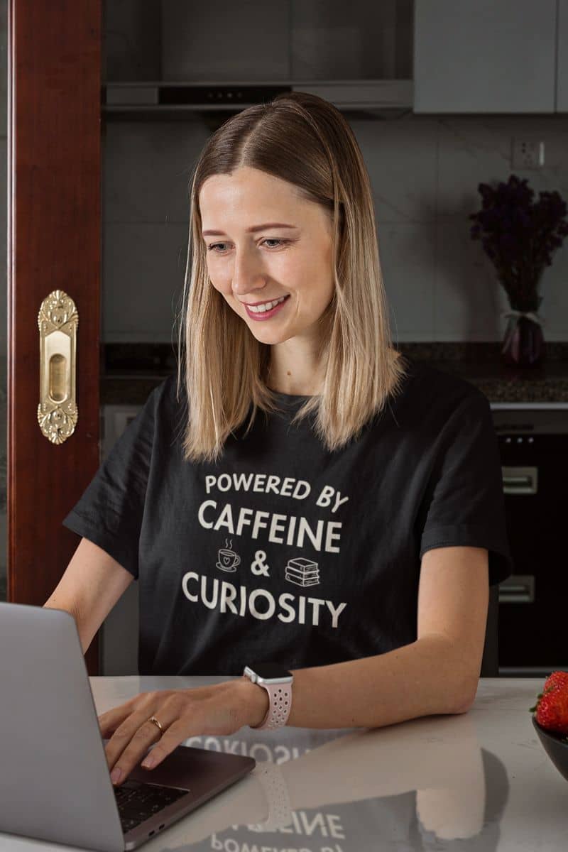 book lover shirt with a woman wearing a t-shirt with text 'Powered by Caffeine & Curiosity'.