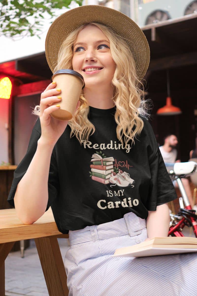 book lover shirts with a woman wearing a t-shirt featuring the text 'Reading is my Cardio', sitting at a coffee shop