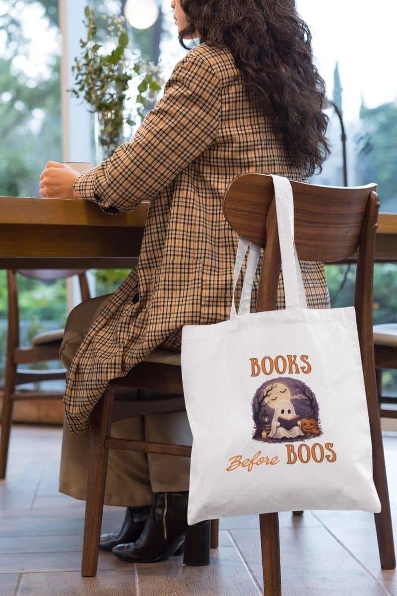 book lover tote bag with a tote bag featuring the text 'Books Before Boos', hanging on the chair