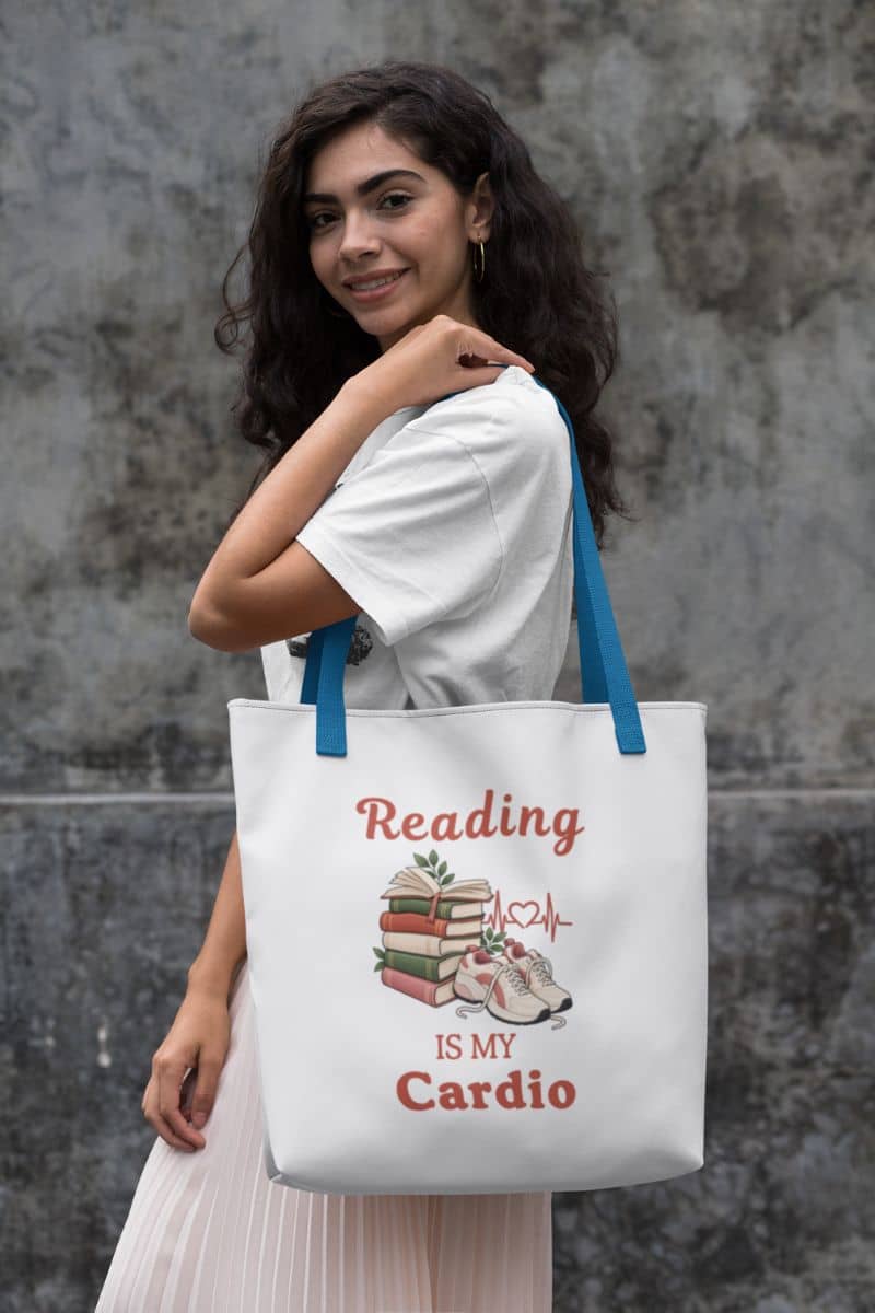 book lover tote with a woman carrying a white tote bag with blue handles. The bag features a graphic print with the text 'Reading IS MY Cardio'