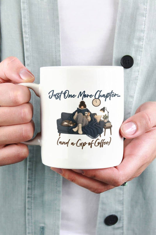 bookish mug with a person holding a white ceramic mug featuring the text that reads 'Just One More Chapter (and a Cup of Coffee)'