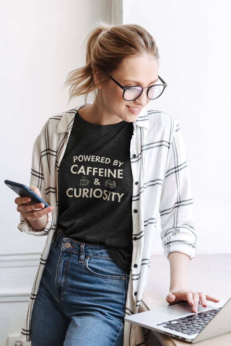 bookish shirt with a woman wearing black t-shirt that reads 'Powered by Caffeine & Curiosity'