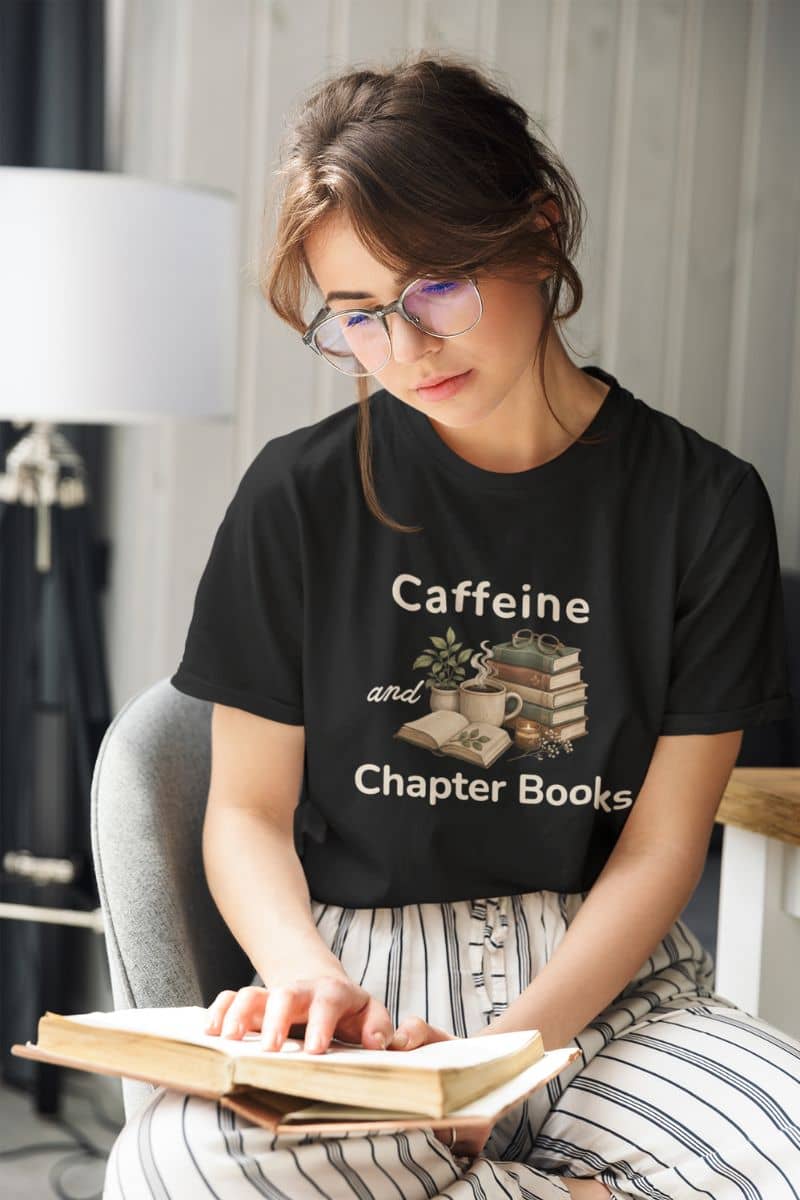bookish shirt with a woman wearing a black graphic t-shirt that reads 'Caffeine and Chapter Books', reading a book. 