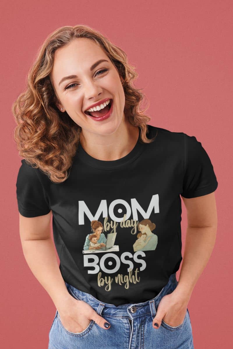 boss mom shirt with a woman wearing a black t-shirt with 'Mom by day, Boss by night' text and graphics on a pink background