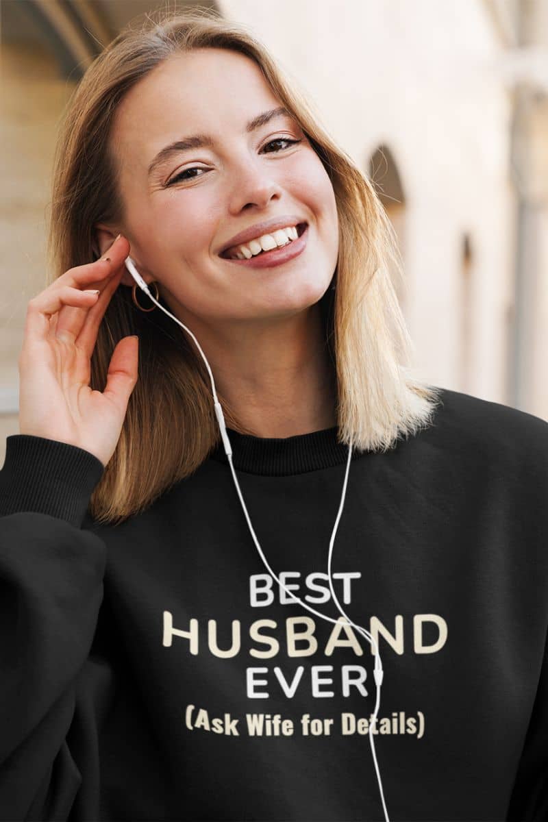 boyfriend girlfriend sweatshirt with a woman wearing a black sweatshirt with text 'Best Husband Ever (Ask Wife for Details)', listening to music.