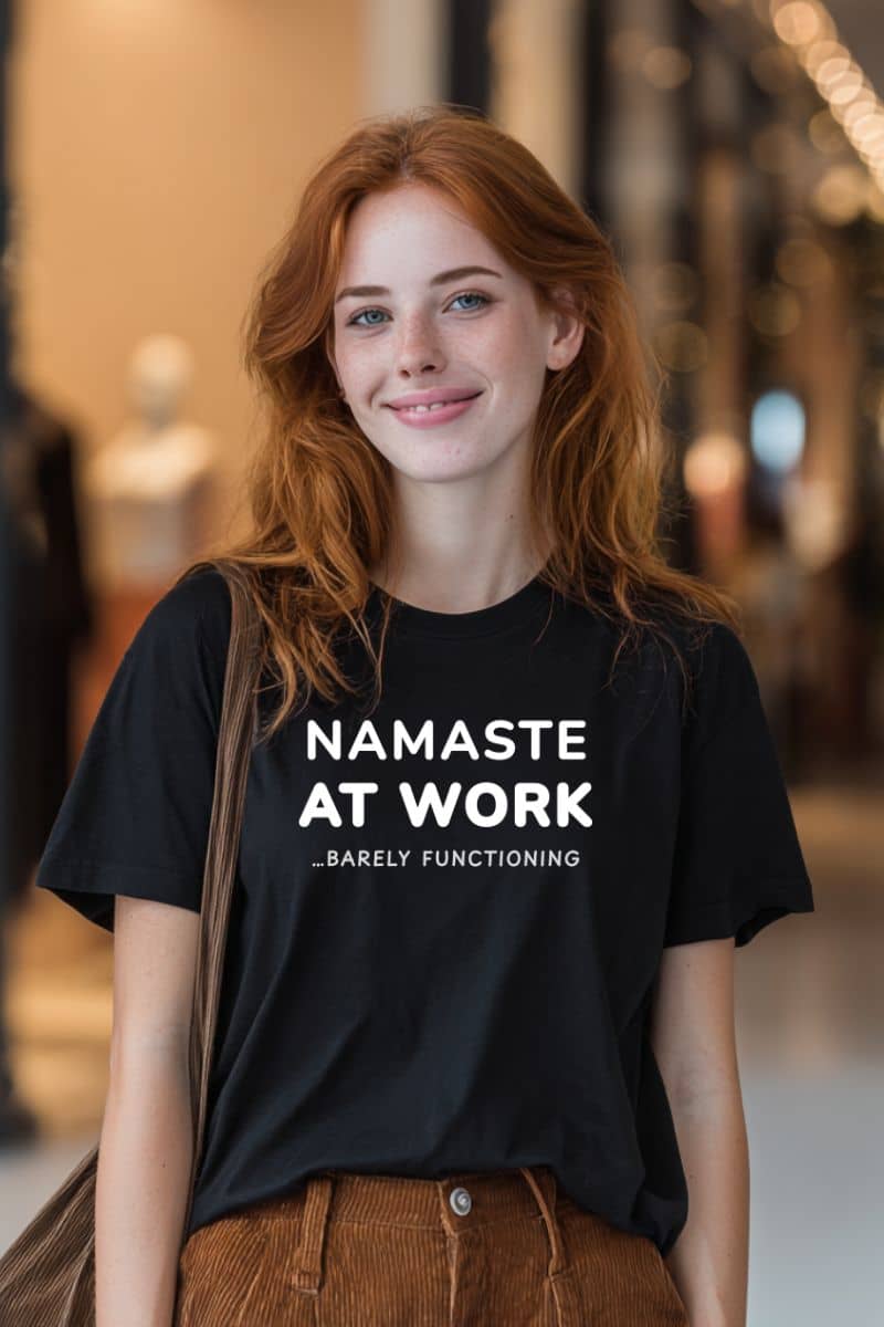 burnout humor shirt with a person wearing a black t-shirt with text 'Namaste at Work...Barely Functioning'.