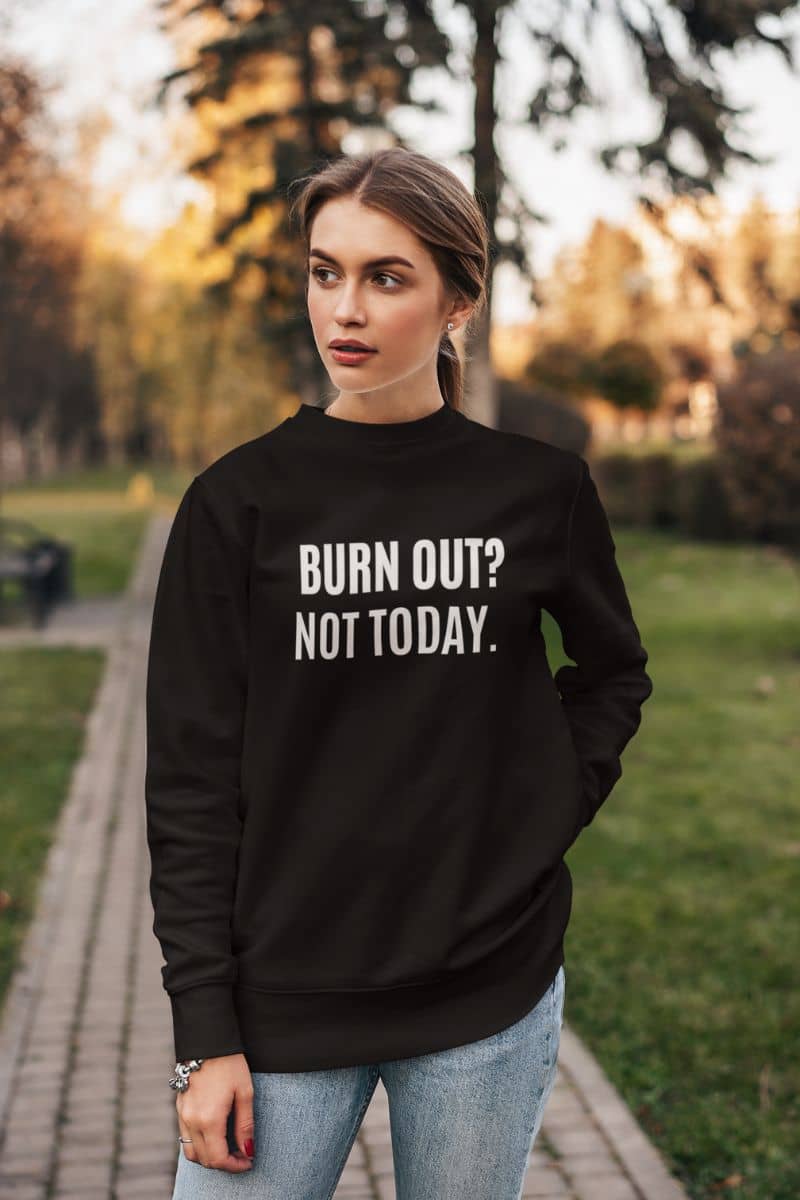 burnout recovery sweater with a woman wearing a black sweatshirt with 'BURN OUT? NOT TODAY.' text in a park.