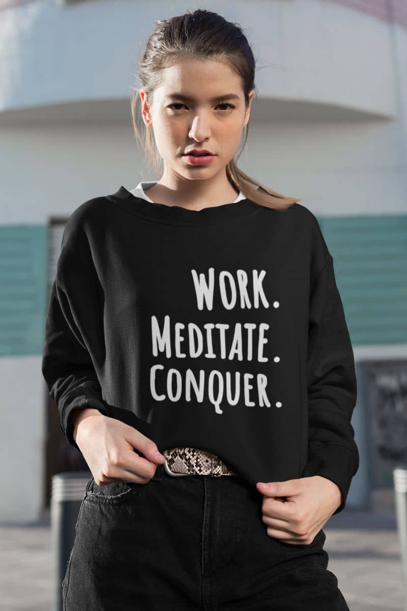 burnout recovery sweater with a person wearing a black sweatshirt with 'WORK. MEDITATE. CONQUER.' text outdoors.