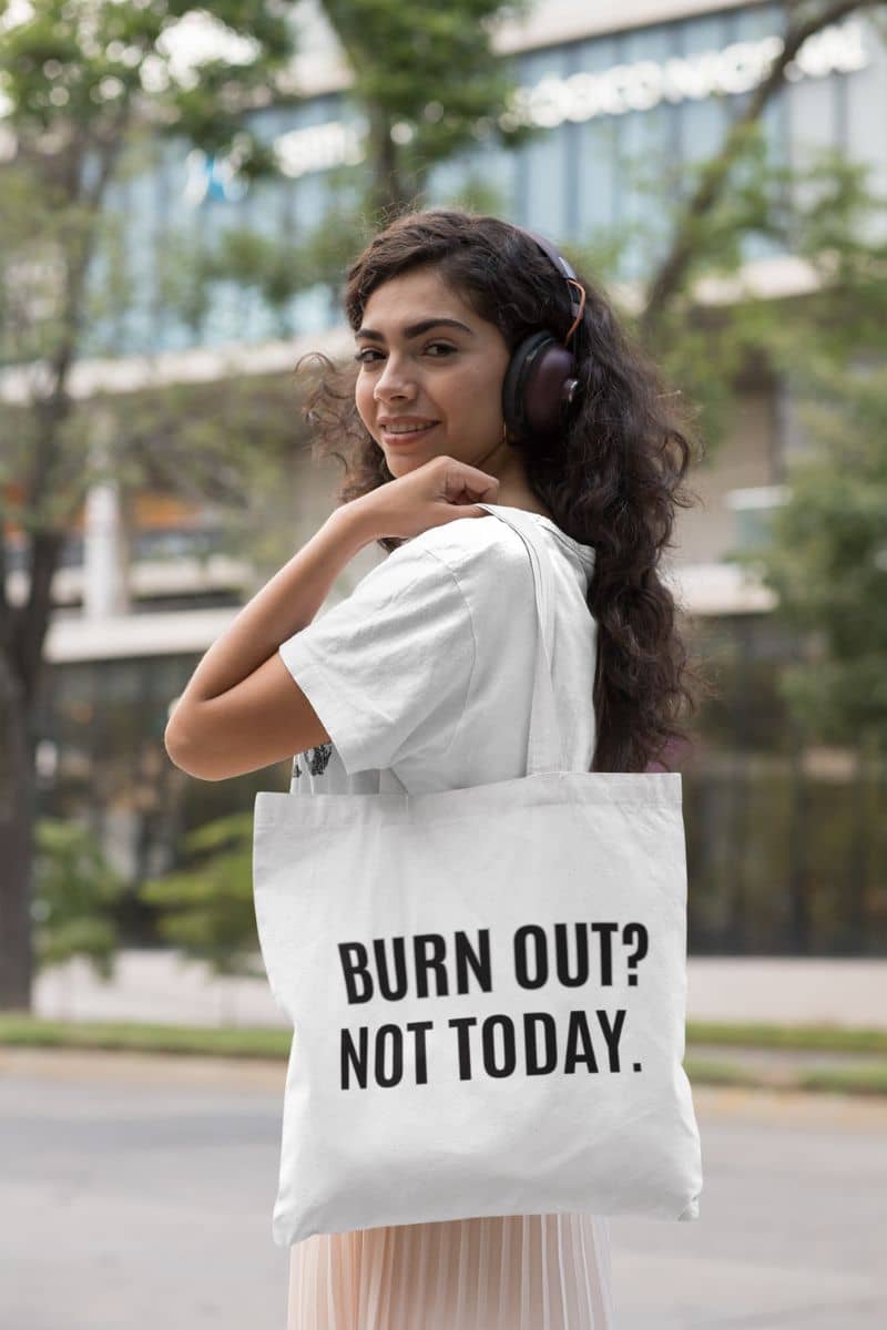 burnout recovery tote with a woman holding a tote bag with 'BURN OUT? NOT TODAY.' text in an urban setting