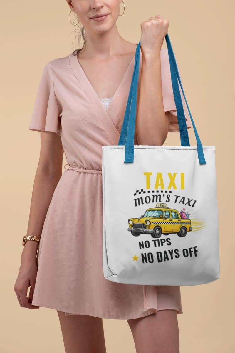 busy mom tote bag with a woman holding a tote bag with text 'Tote bag with black handle featuring the  text 'Taxi, Mom’s Taxi – No tips, no days off' on a beige background