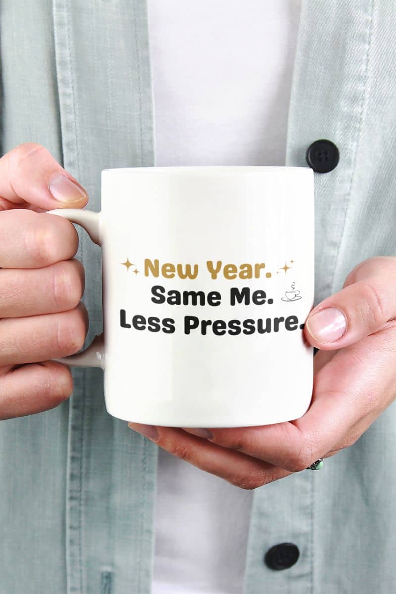 calm morning mug with a person holding a mug with 'New Year. Same Me. Less Pressure.' text