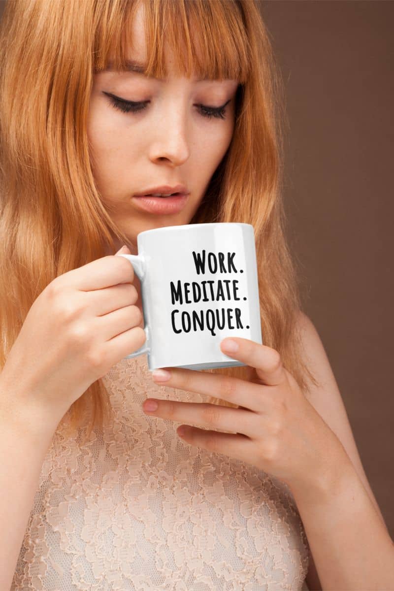 calm productivity mug with a woman holding a mug with 'Work. Meditate. Conquer.' text on a brown background