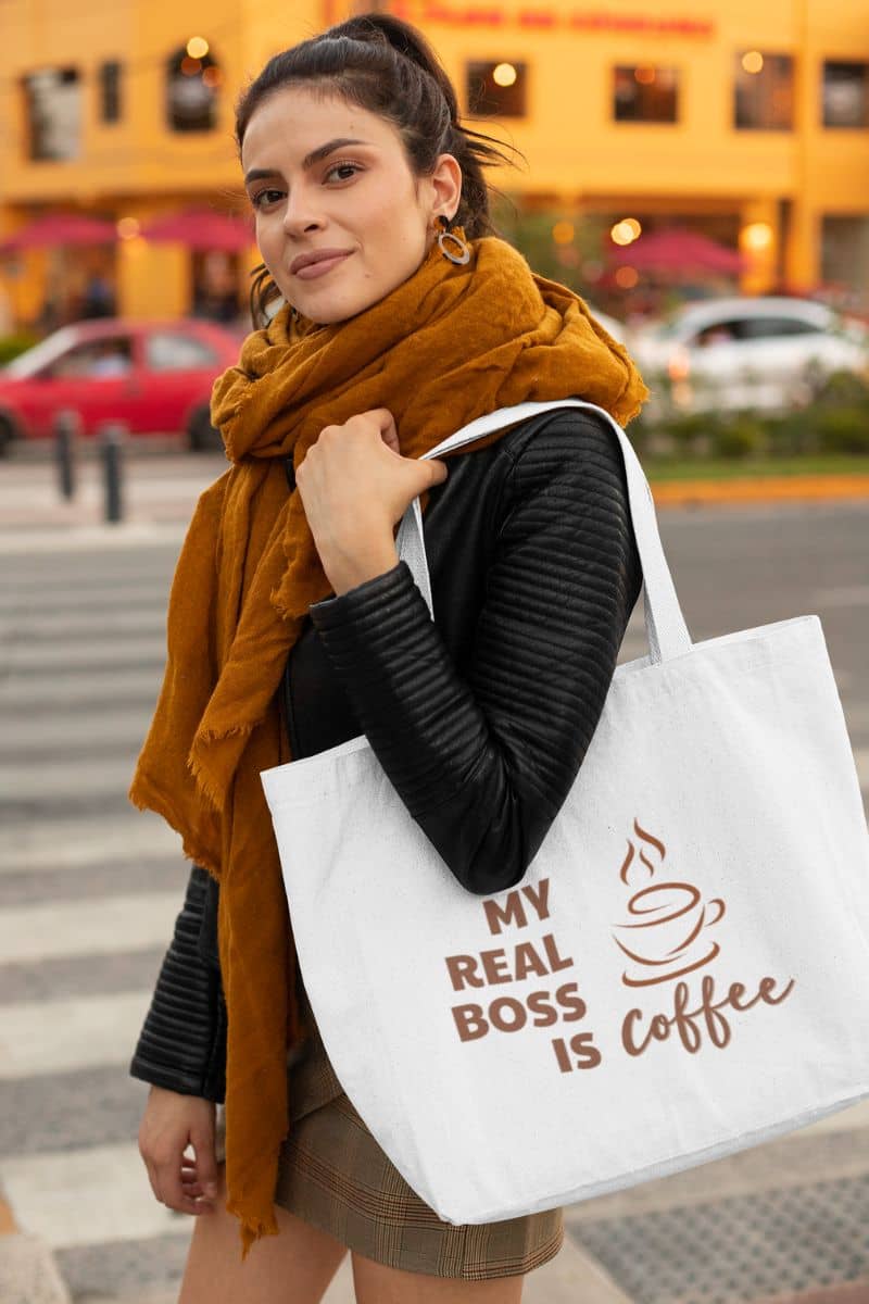 canvas printed tote bag with a woman holding a tote bag with 'My Real Boss is Coffee' text in an urban setting
