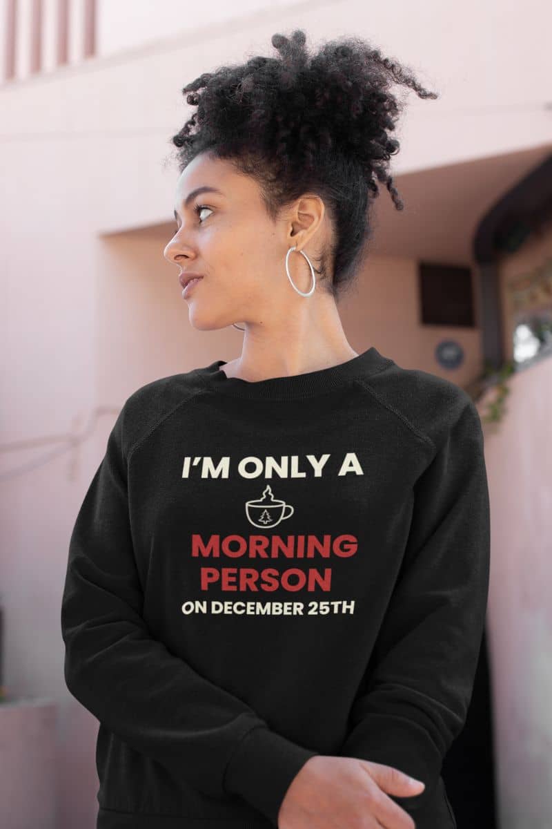christmas caffeine sweater with a person wearing a black sweatshirt with humorous text 'I’m Only a Morning Person on December 25th'